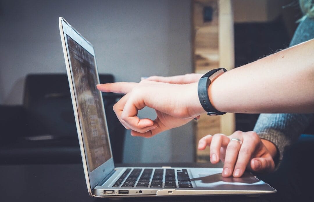 Two people using a laptop, one pointing at the screen